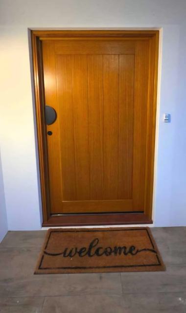 Golden timber front door on a tiled porch